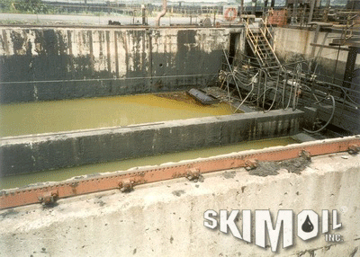 Drum skimmer operating in a collection pit removing oil from the water
